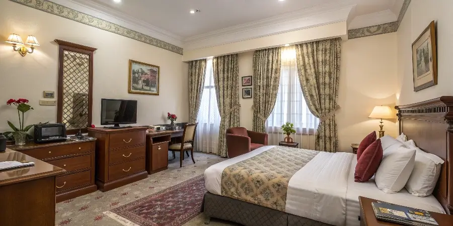 A stylishly furnished hotel room with a bed, desk, and wardrobe